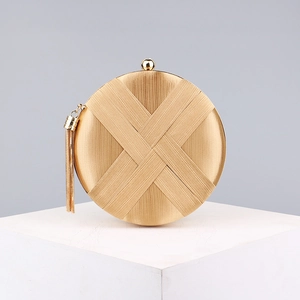 Detailed close-up of a gold round evening bag with woven satin texture and metallic tassel