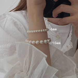 Detail showing 6mm and 10mm cream white pearl stretch bracelets worn together