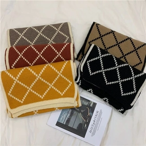 Close-up of five colorful knitted plaid scarves neatly folded on white fabric