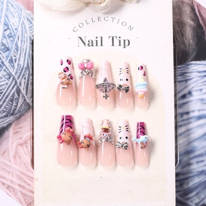 Detailed view of pink press-on nails with Hello Kitty charms and pearls on card