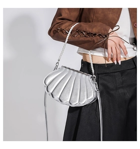 Detail der silbernen muschelförmigen Umhängetasche mit Perlenkette und Metallic-Finish