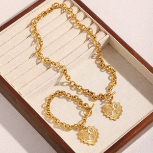 Détail du collier et bracelet à mailles épaisses dorés 18K avec pendentif cœur LOVE