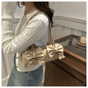 Détail du sac polochon beige avec de grands nœuds décoratifs et une bandoulière fine