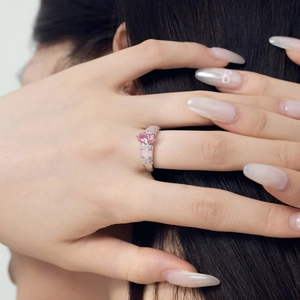 Close-up of pink oval gemstone ring with diamond accents on a female hand