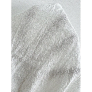 Close-up of white textured cotton linen fabric with fine striped weave and soft folds
