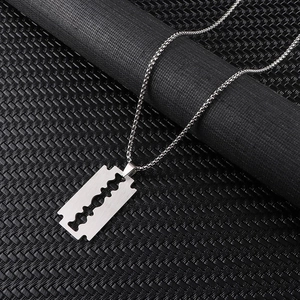 Close-up of a silver stainless steel razor blade pendant with a fine box chain