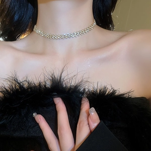 Close-up of sparkling rhinestone choker necklace on model with black feather detail