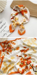 Detailed view of silk square scarf featuring warm orange persimmon patterns and elegant drape