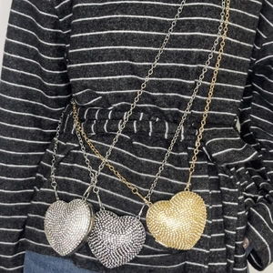 Close-up of heart-shaped rhinestone mini bags in gold and silver with metal chain