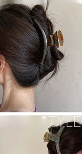 Detail of tortoise shell and blue gold acetate hair claws styled on long hair