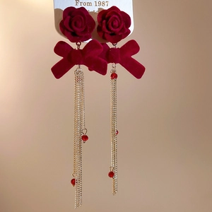 Detail of red velvet rose earrings with bowknot and golden long chain tassels