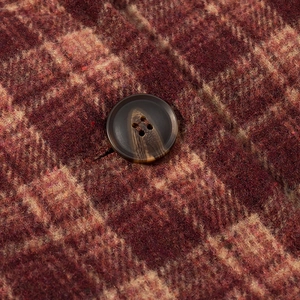 Macro shot of red-brown plaid wool fabric texture and vintage four-hole button detail