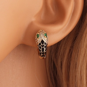 Close-up of gold snake hoop earring with micro-pave crystals and green gemstone eyes