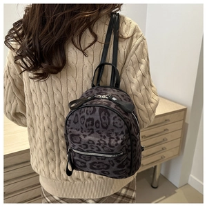 Detailed close-up of a leopard print mini backpack featuring silver hardware and faux fur texture