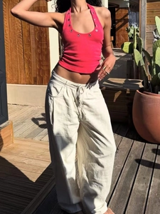 Top allacciato al collo rosa con occhielli metallici e pantaloni beige larghi estivi
