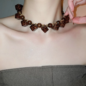 Detail of wooden beads and leopard print acrylic necklace on model neck