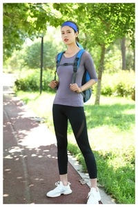 Outdoor fitness set with purple top and black leggings on a scenic park path