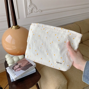 Close-up of floral embroidery on cream cotton fabric makeup bag with yellow daisy details