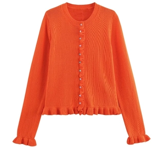 Détail d'un cardigan en tricot orange avec bords à volants et boutons argentés