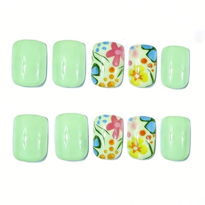 Detailed view of short square press-on nails with green base and floral leaf patterns