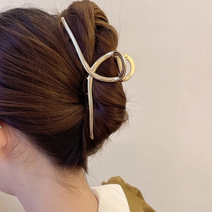 Side view of large golden metal shark hair claw clip holding a secure hair bun style