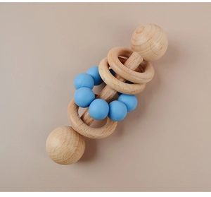 Macro detail of natural beech wood baby rattle with soft blue silicone teething beads