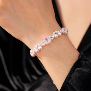 Detail of double-row pearl bracelet with a pink centerpiece and zircon pave setting