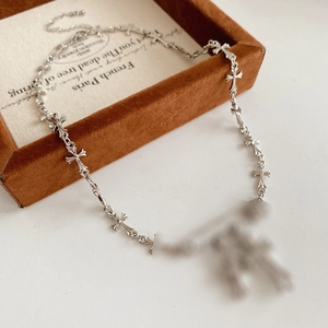 Detailed view of silver cross necklace chain draped over a brown velvet jewelry box