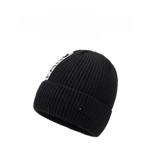 Close-up of thick ribbed knit texture and letter patch detail on a black winter beanie