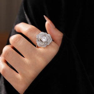 Close-up of sparkling zircon flower ring with oval center stone on model's finger