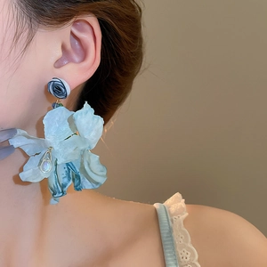 Detail of light blue fabric flower earrings with layered petals on female model side profile