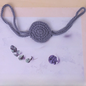 Detailed view of gray crochet knitted nose accessory with woven lanyards and texture