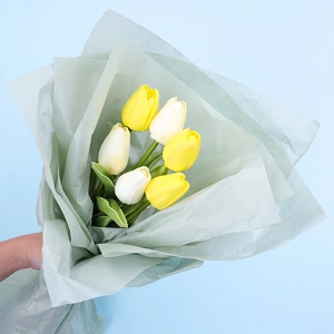 Artificial tulip bouquet in white and yellow colors wrapped in light green floral paper
