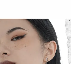 Close-up of asymmetrical liquid metal silver studs worn on ear with modern art style