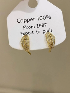 Macro shot of gold-plated copper feather stud earrings with micro-set cubic zirconia stones