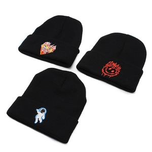Three black knitted beanies with astronaut and flame heart embroidery on white background