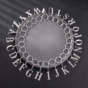 Polished stainless steel A-Z initial letter keychains set on a dark textured tray