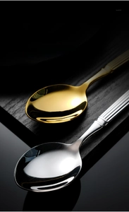 Detailed close-up of golden and silver stainless steel spoons with fluted handle texture