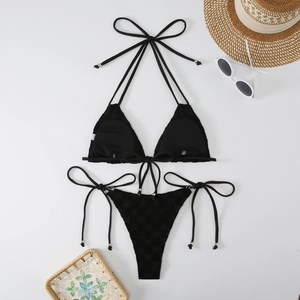 Flat lay of black halter bikini with silver bead accents and beach vacation accessories