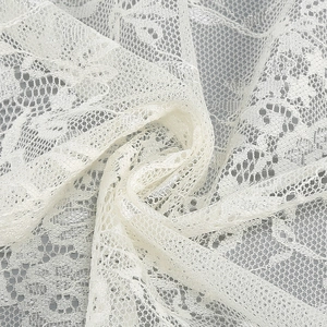 Detailed close-up of white floral lace fabric with intricate hollow-out embroidery texture