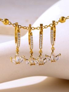Close-up of gold clover earrings with micro-pave zircons hanging on a fine chain