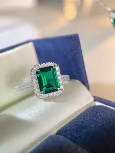 Macro shot of an emerald cut green gemstone ring in a classic halo pavé setting