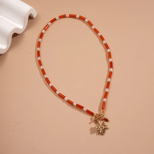 Retro beaded necklace with maple leaf pendant and gold toggle clasp on a beige background
