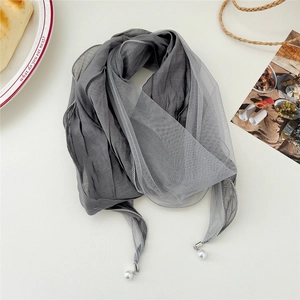 Detail of grey silk scarf with lace stitching and elegant pearl pendant tassels