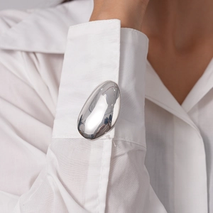 Close-up of polished silver oval cufflinks on a white shirt cuff for men and women