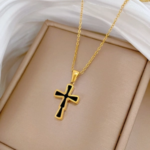 Detail of a gold titanium steel cross necklace with black enamel inlay in a luxury jewelry box