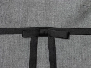 Close-up detail of grey twill fabric and premium black satin bow tie on a mini dress