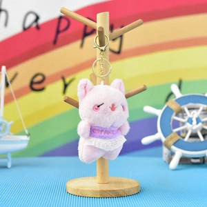 Close-up of cute pink plush cat keychain with purple shirt and white lace skirt