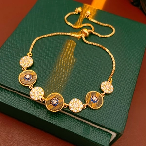 Close-up of gold-plated bracelet with tiger eye stone and star zircon charms on green box