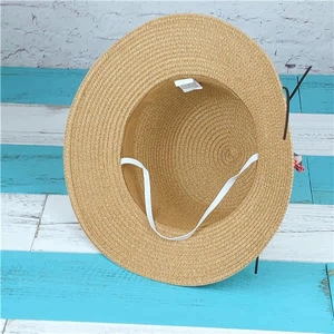 Dettaglio del cappello di paglia beige con cordino elastico e fiocco a scacchi rossi